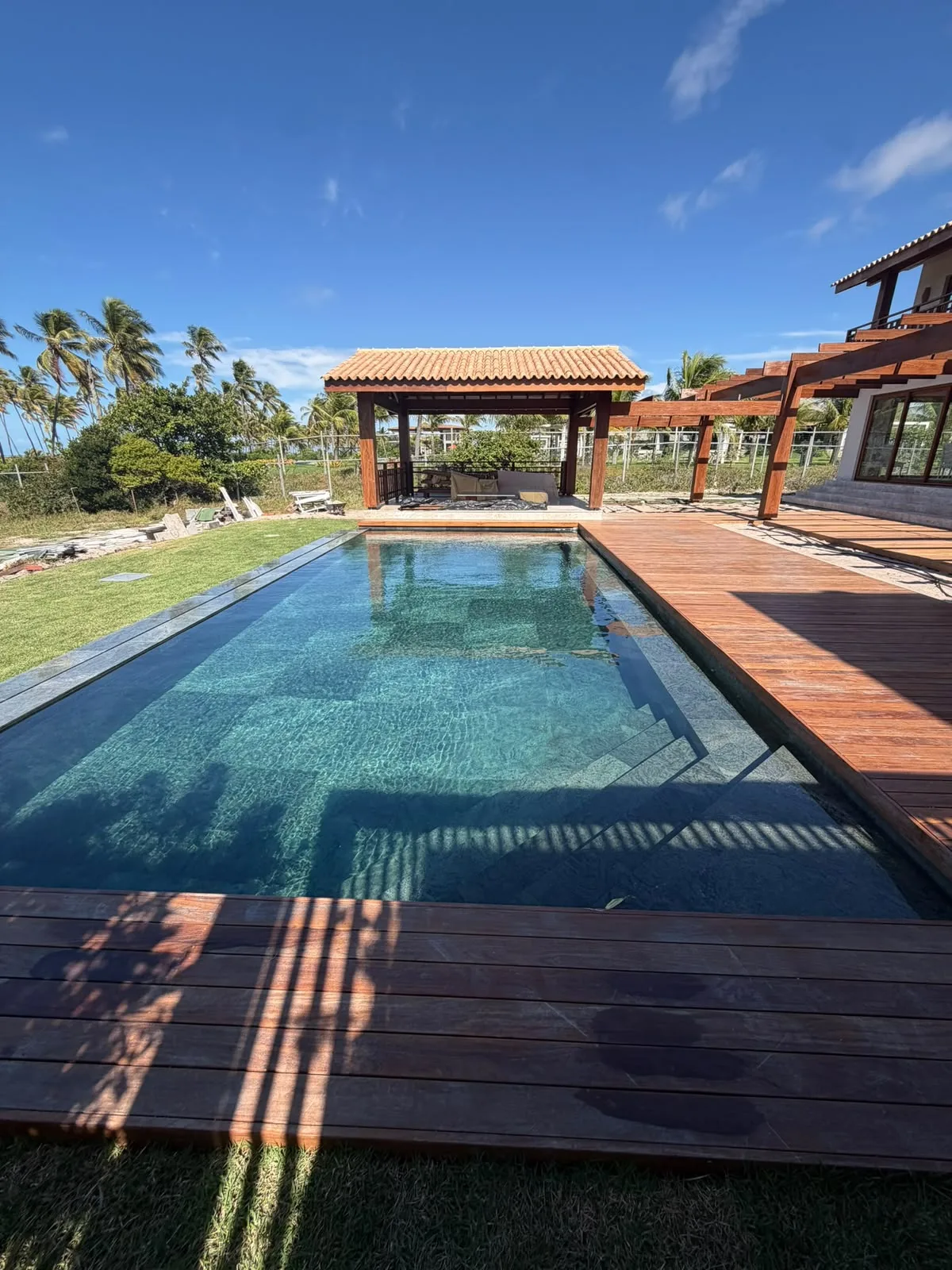Deck e pavilhão em madeira junto à piscina da Casa D’Ávila, em Praia do Forte