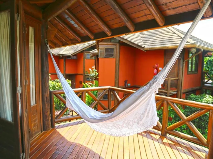Varanda de bangalô com cobertura e guarda-corpo de madeira na Pousada Triboju em Fernando de Noronha